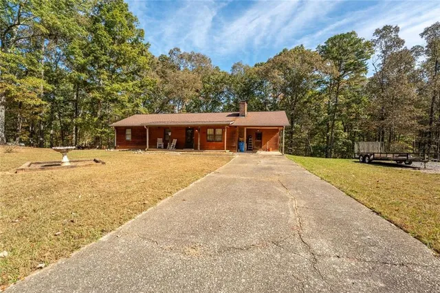 a view of house with yard and trees in the background