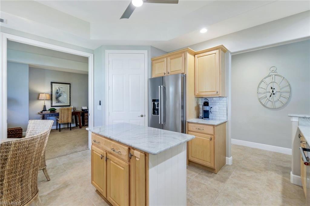 19620 Marino Lake Circle, Unit 2802 Fort Myers, FL 33913 - Photo 18 of 38 Kitchen featuring light stone countertops, light brown cabinets, a ceiling fan, backsplash