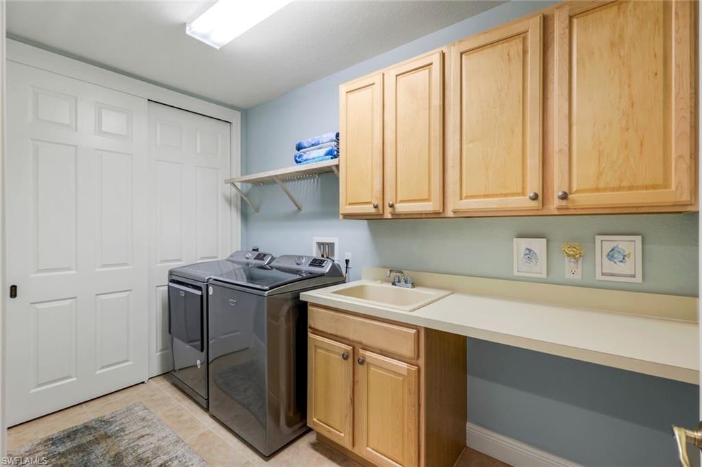 19620 Marino Lake Circle, Unit 2802 Fort Myers, FL 33913 - Photo 27 of 38 Laundry room with cabinet space, light tile patterned floors, a sink, and washer and clothes dryer