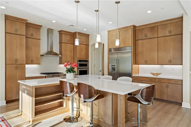 a kitchen with stainless steel appliances kitchen island granite countertop a refrigerator a stove and a dining table with wooden floor