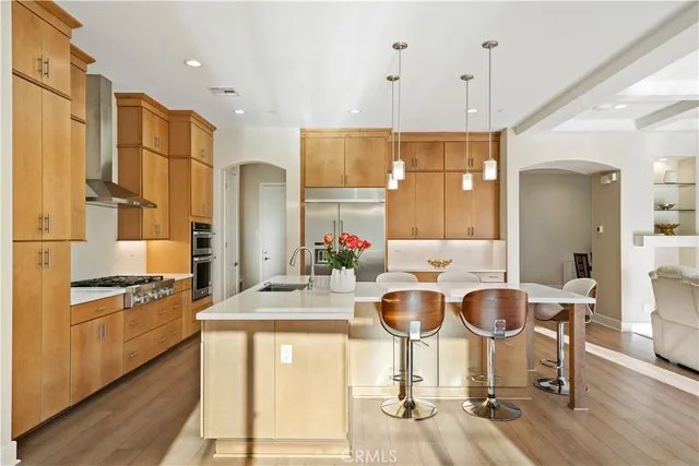 a kitchen with stainless steel appliances granite countertop a dining table chairs and a refrigerator