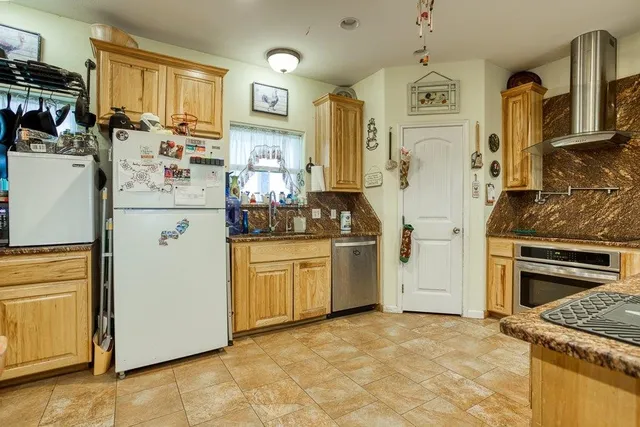 a kitchen with stainless steel appliances granite countertop a refrigerator a stove and a sink
