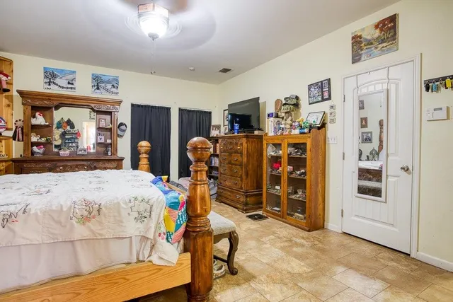 a bedroom with a bed a dresser and potted plants on the table