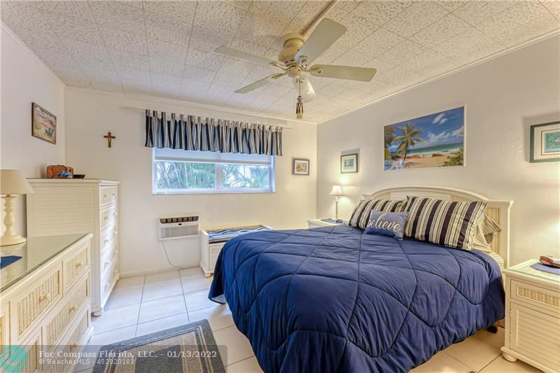 1210 North Riverside Drive, Unit 107 Pompano Beach, FL 33062 - Photo 4 of 29 a bedroom with a bed and a chandelier