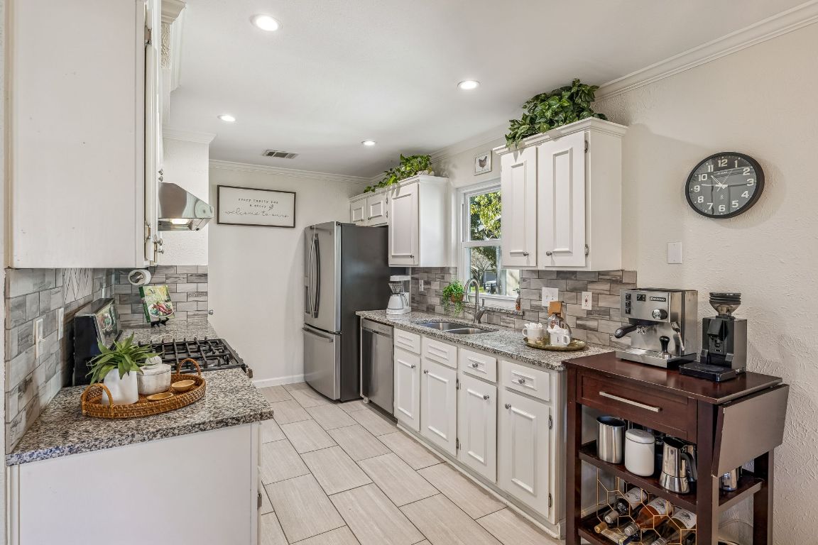 5502 Porsche Lane Austin, TX 78749 - Photo 14 of 32 Kitchen with white cabinetry, light stone counters, ornamental molding, stainless steel appliances, and tasteful backsplash