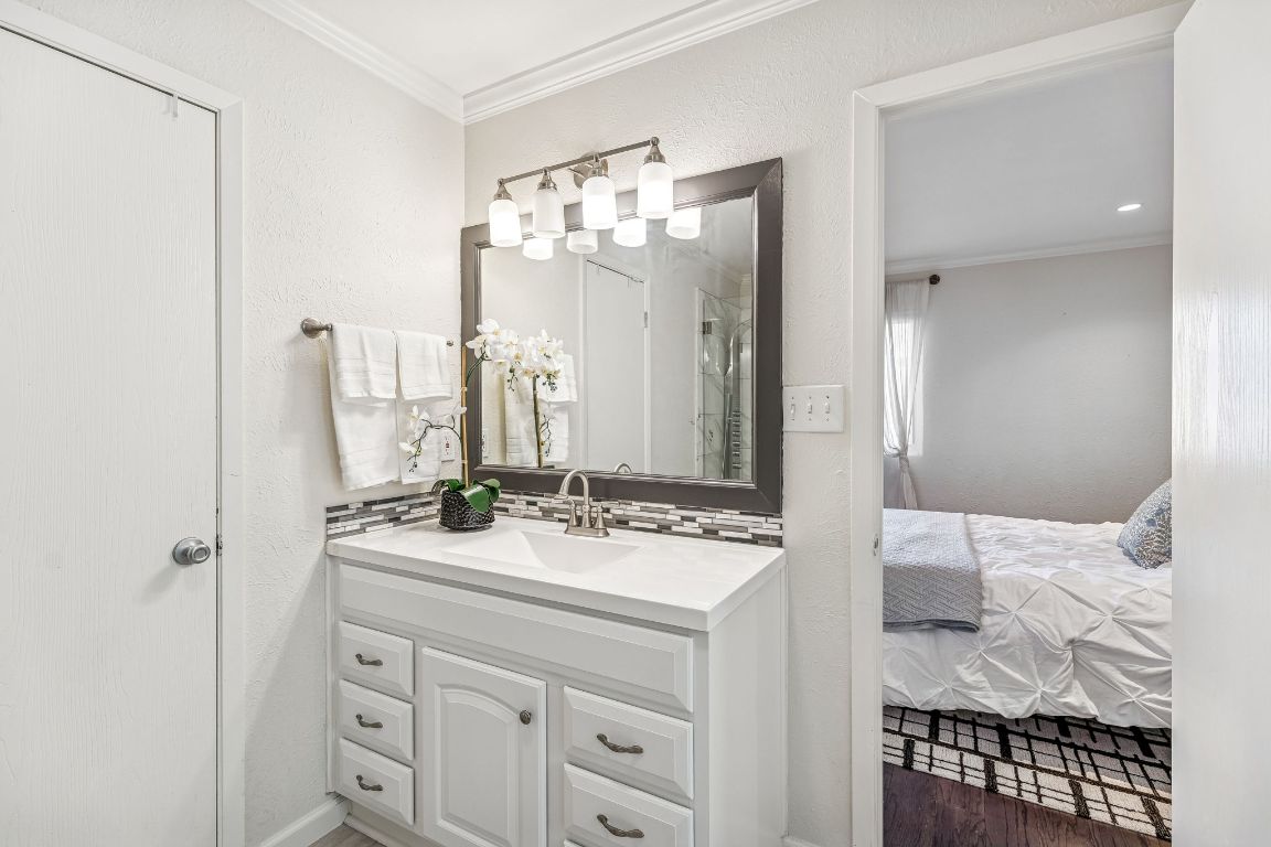 5502 Porsche Lane Austin, TX 78749 - Photo 20 of 32 Full bathroom with a textured wall, crown molding, vanity, ensuite bathroom, and a shower stall