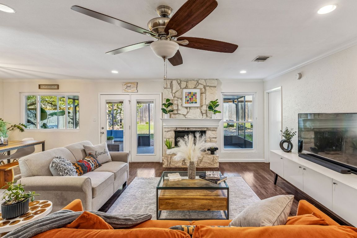 5502 Porsche Lane Austin, TX 78749 - Photo 6 of 32 Living room featuring crown molding, wood finished floors, a stone fireplace, recessed lighting, and ceiling fan