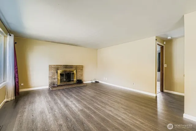 an empty room with wooden floor and fireplace