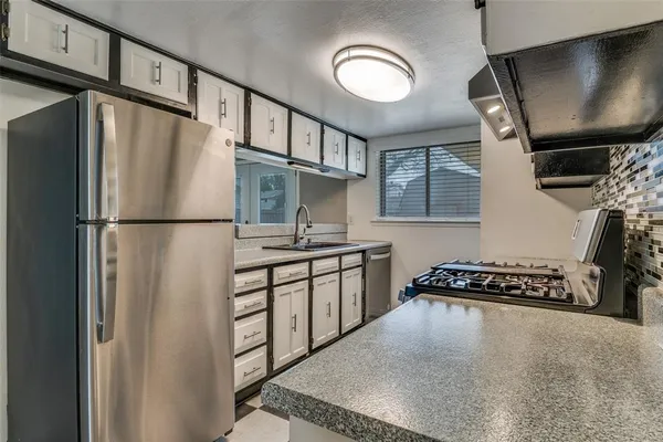 a kitchen with stainless steel appliances granite countertop a refrigerator a stove and a sink with wooden floor