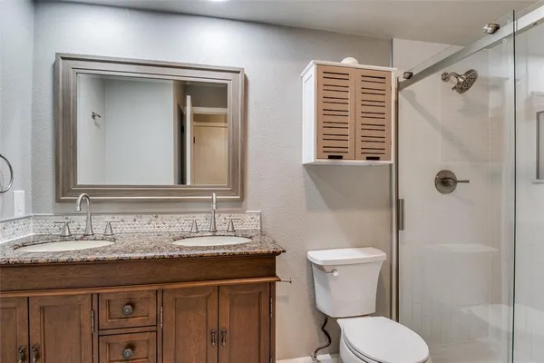 a bathroom with a granite countertop toilet sink and mirror
