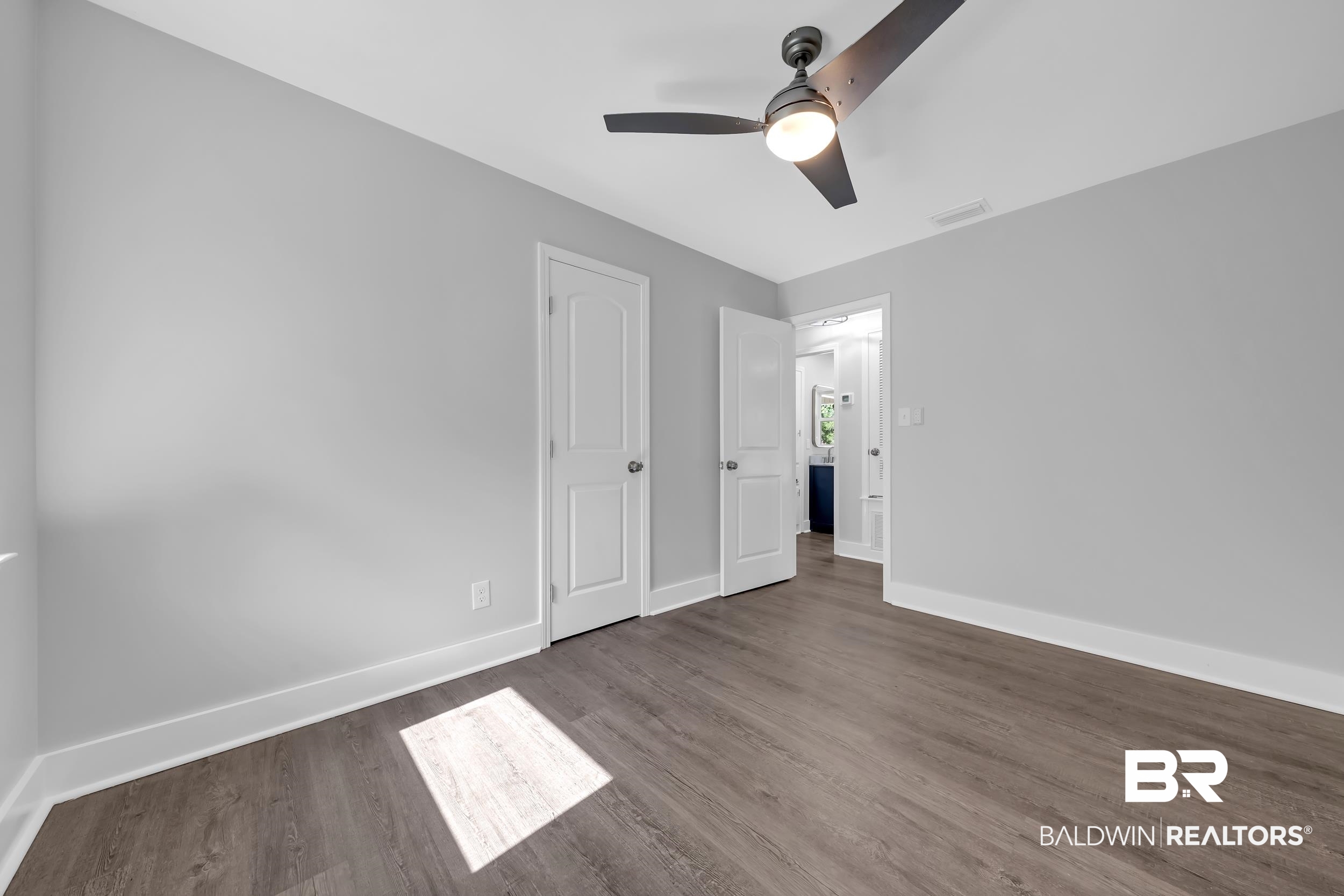 2712 Shelton Beach Rd Extension Mobile, AL 36613 - Photo 13 of 24 Spacious room featuring wood-finish flooring, light grey walls, and a contemporary ceiling fan with integrated lighting
