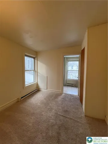 a view of an empty room with window and closet area