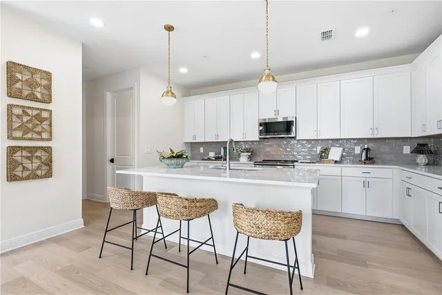 a kitchen with stainless steel appliances granite countertop a sink a stove and microwave with wooden floor