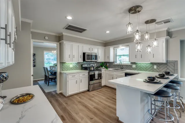 a kitchen with a refrigerator a stove a sink dishwasher a oven with white cabinets and wooden floor