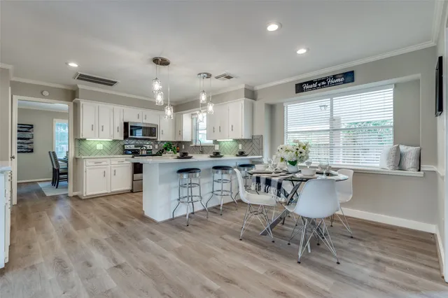 a kitchen with stainless steel appliances kitchen island granite countertop a stove a sink a dining table and chairs