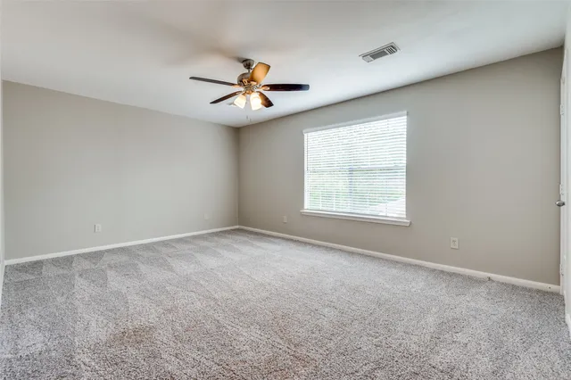 an empty room with windows and fan
