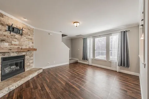 a view of a livingroom with wooden floor and a kitchen