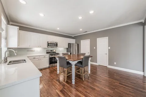 a kitchen with stainless steel appliances granite countertop a dining table chairs refrigerator and microwave