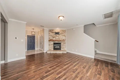 a view of an empty room with wooden floor fireplace and a window