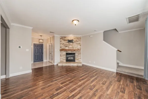 a view of an empty room with wooden floor fireplace and a window