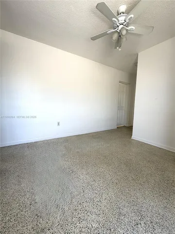 an empty room with a fan & a ceiling fan