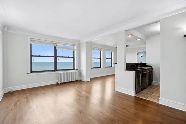 a view of an empty room with a window and wooden floor