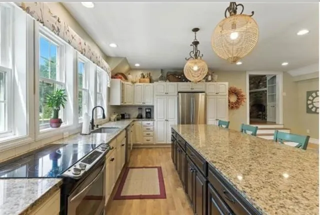 a large kitchen with kitchen island granite countertop a large window and a sink