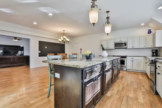 a kitchen with stainless steel appliances granite countertop a stove top oven a sink dishwasher and a refrigerator with wooden floor