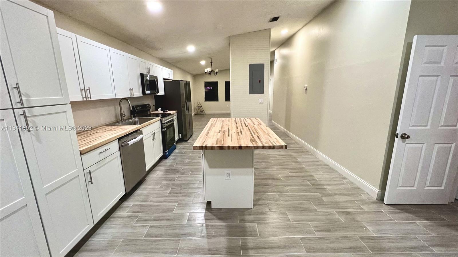 Sunset Miami, FL 33173 - Photo 9 of 41 a large kitchen with white cabinets and stainless steel appliances