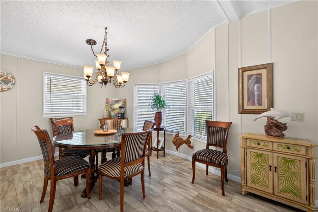 212 Oceans Boulevard, Unit 212 Naples, FL 34104 - Photo 8 of 30 a dining room with furniture a chandelier and wooden floor