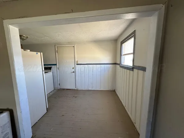 a view of a hallway with a refrigerator in kitchen