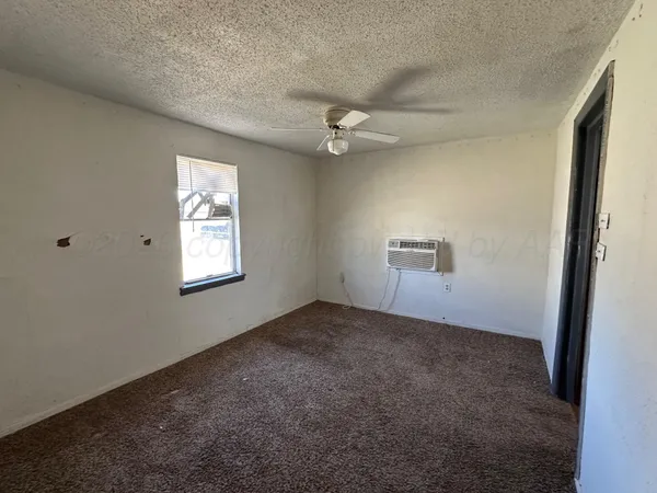 an empty room with windows and fan