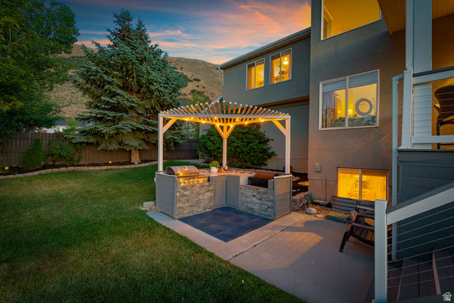 14883 Tooele Lane Draper, UT 84020 - Photo 47 of 49 Outdoor kitchen featuring built-in grill, stone veneer accents, and a slatted pergola