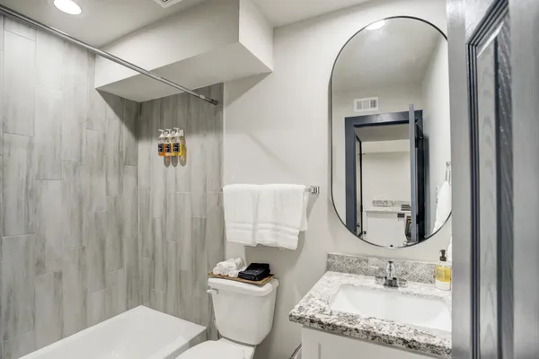 a bathroom with a granite countertop sink mirror vanity and toilet