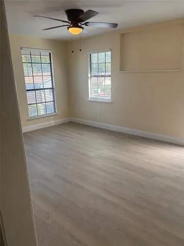 an empty room with windows and fan