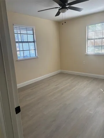 an empty room with windows and fan