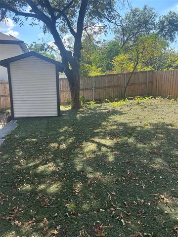 a view of a backyard with a tree and wooden fence