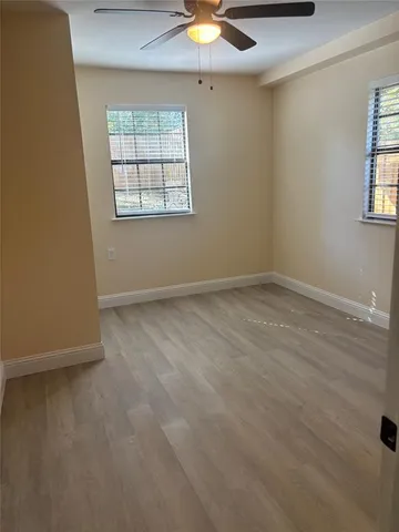 an empty room with windows and fan