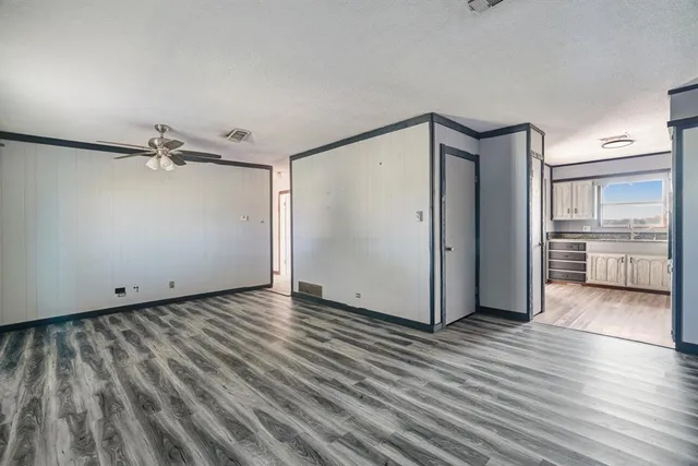 a view of a big room with wooden floor and a kitchen