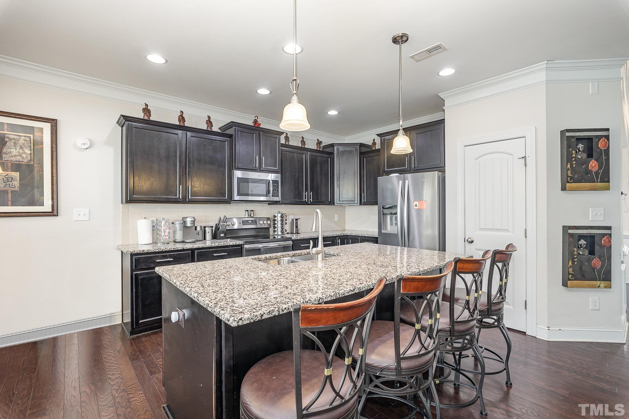 1513 Slate Ridge Road Knightdale, NC 27545 - Photo 12 of 36 a kitchen with granite countertop a table chairs microwave and refrigerator