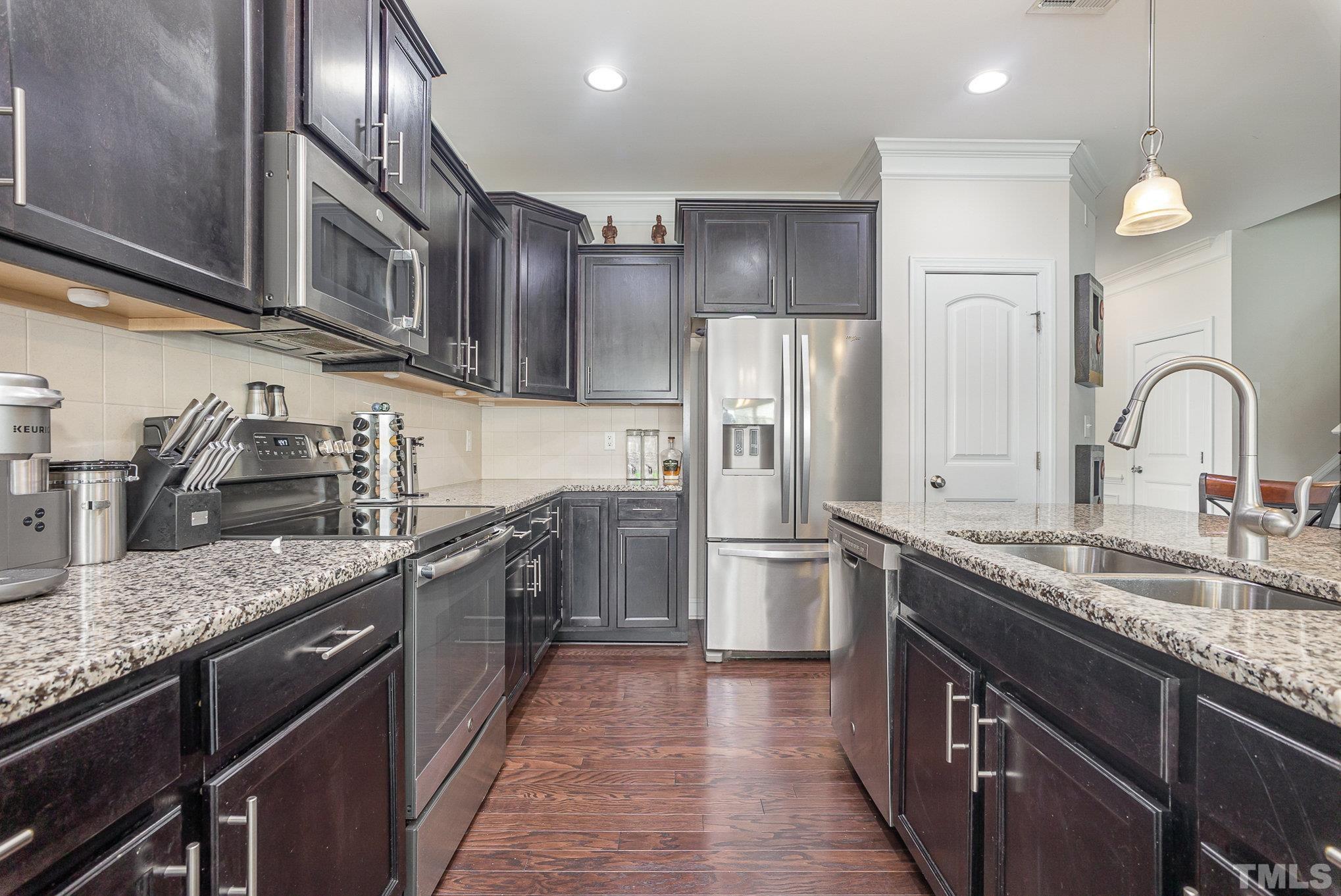 1513 Slate Ridge Road Knightdale, NC 27545 - Photo 13 of 36 a kitchen with stainless steel appliances granite countertop a sink stove refrigerator and cabinets