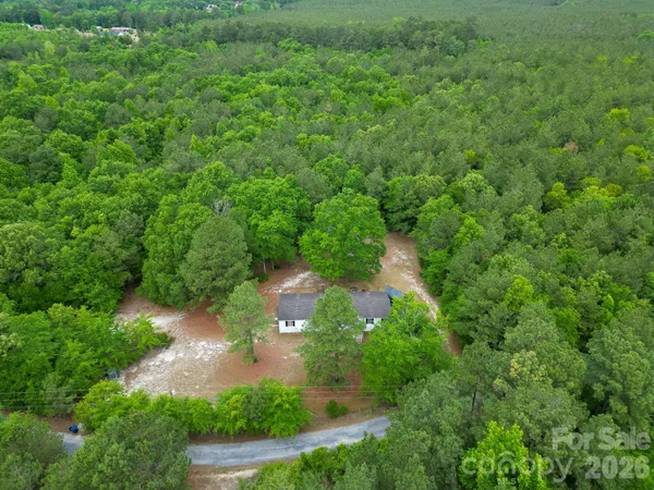 an aerial view of residential house with outdoor space and trees all around