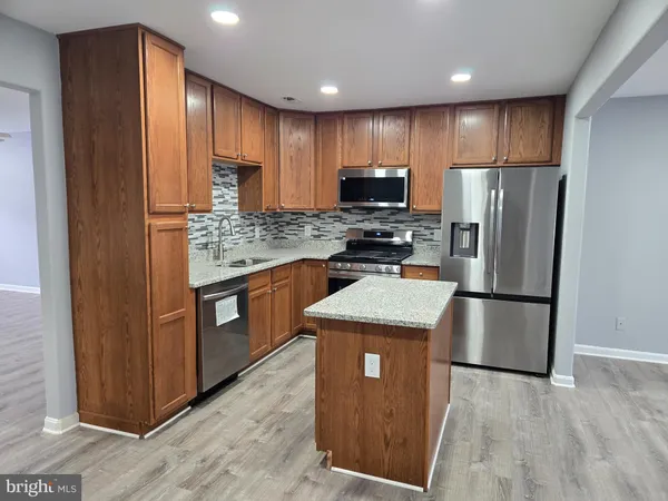 a kitchen with stainless steel appliances granite countertop a refrigerator a stove a sink and a microwave