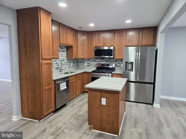 a kitchen with stainless steel appliances granite countertop a refrigerator a stove a sink and a microwave