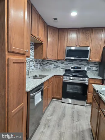 a kitchen with stainless steel appliances granite countertop wooden cabinets a stove top oven a sink and dishwasher