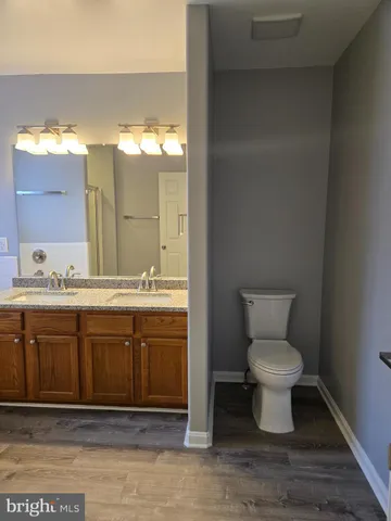 a bathroom with a granite countertop toilet a sink and a mirror