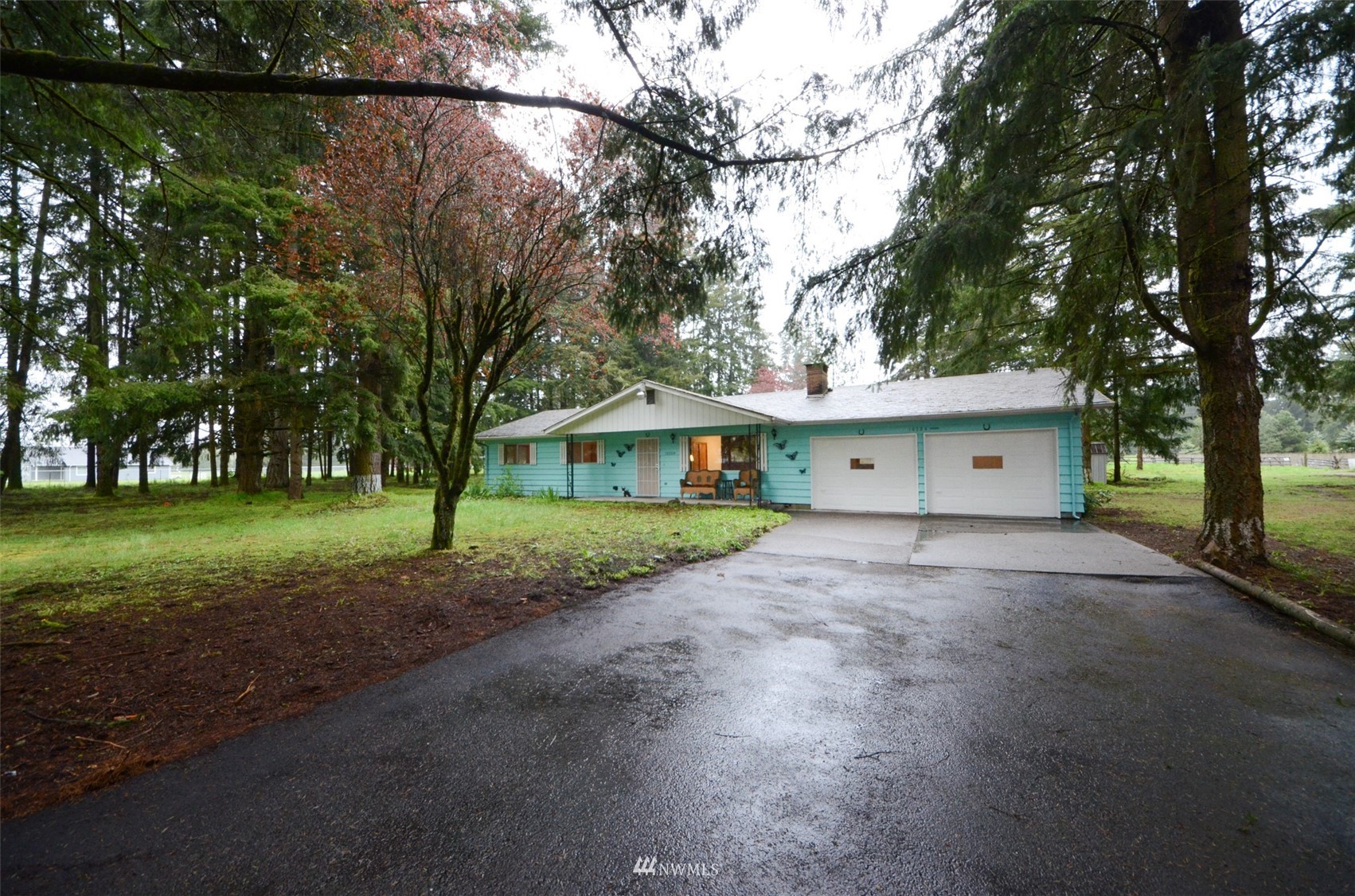 a view of a house with a yard and large trees