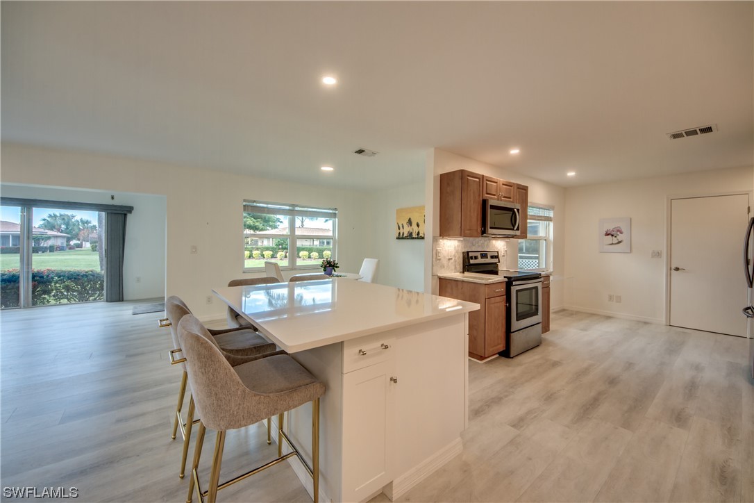 5585 Buring Court Fort Myers, FL 33919 - Photo 6 of 34 a kitchen with microwave a refrigerator and chairs