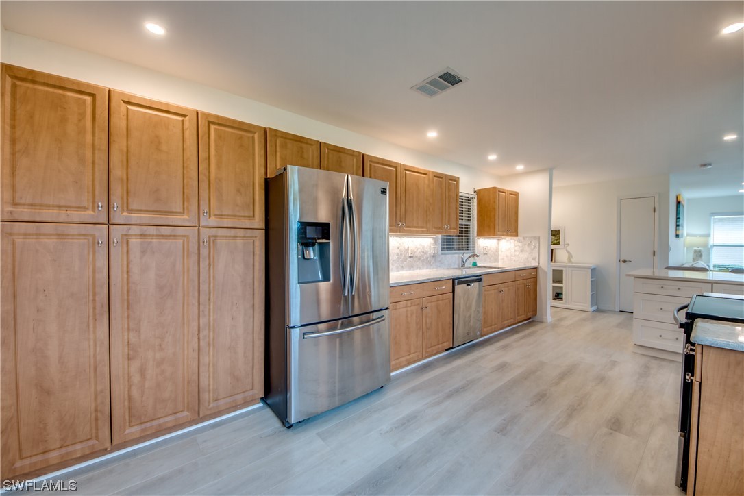 5585 Buring Court Fort Myers, FL 33919 - Photo 10 of 34 a kitchen with stainless steel appliances a refrigerator and wooden cabinets