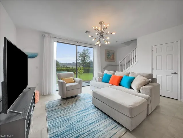 a living room with furniture flat screen tv and a large window